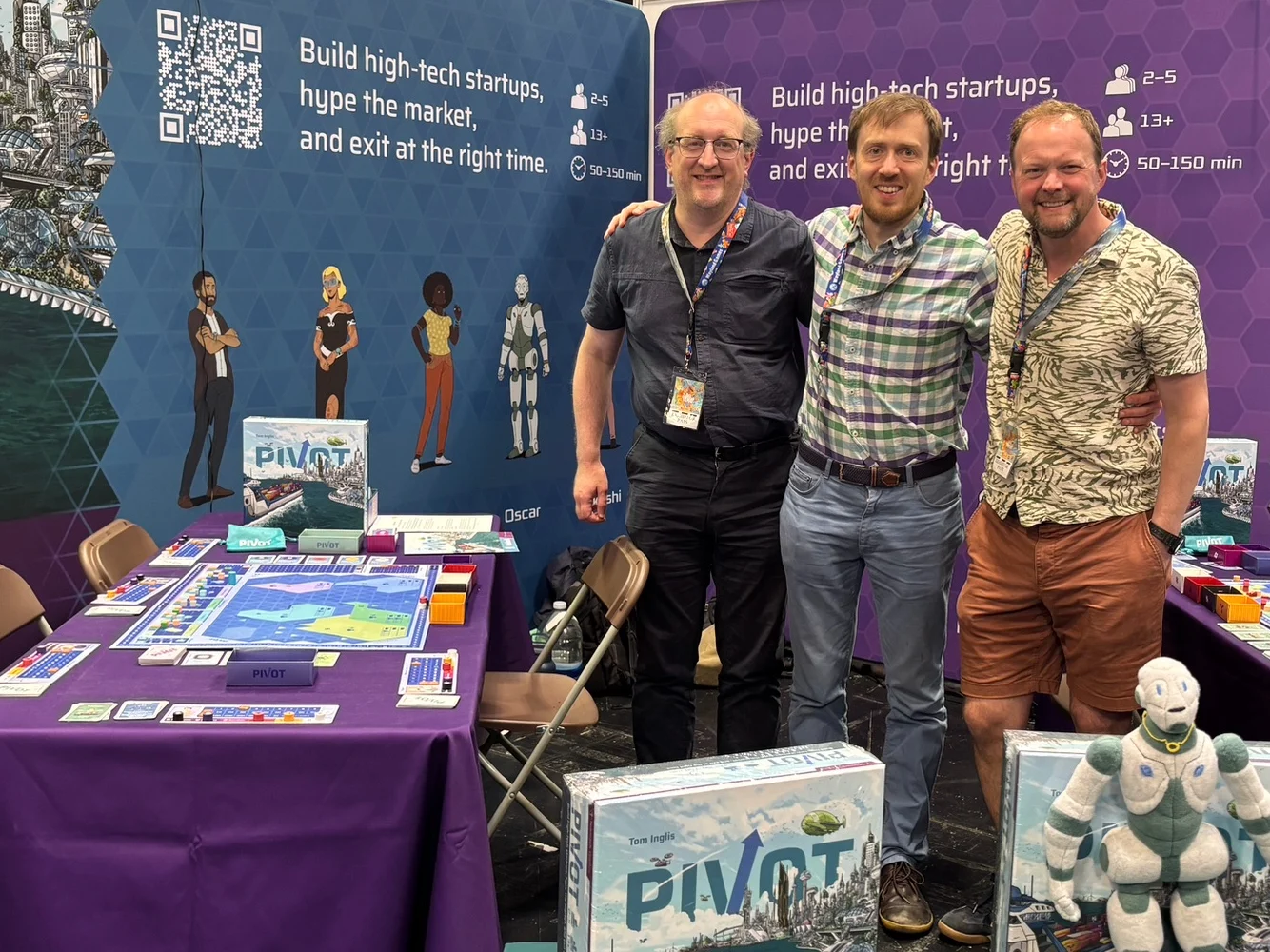 The Teòmach Games team behind the Pivot stand at UK Games Expo, with Oscar the robot mascot